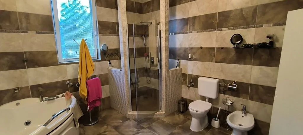 Tágas fürdőszoba sarokkáddal, zuhanykabinnal, WC-vel és bidével