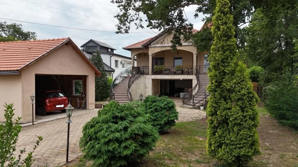 A családi ház kerti homlokzata, különálló gépkocsitárolója és terasza